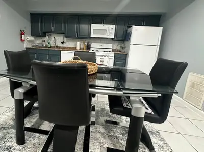 a kitchen with a glass table and black chairs at Luxury 2-Bedrooms 2-Bathrooms Near NYC/EWR in Newark