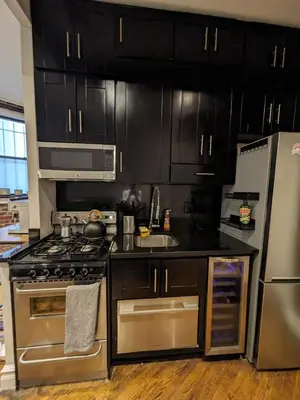 a kitchen with stainless steel appliances and black cabinets at Private Room at a shared Apartment at the Heart of East Village in New York