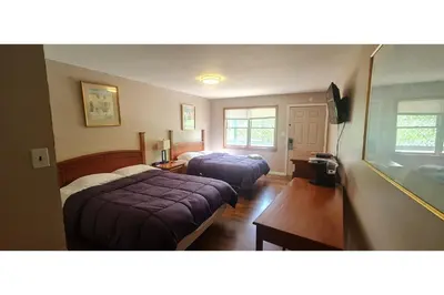a hotel room with two beds and a desk at Werry's Cottages Motel & Pub by OYO East Stroudsburg Poconos in East Stroudsburg
