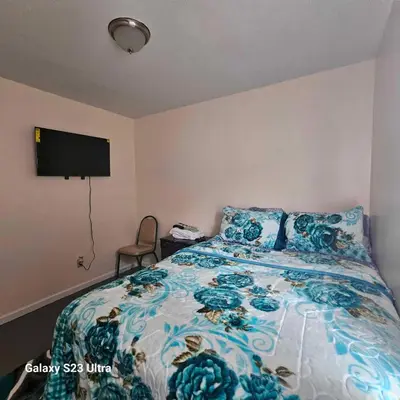 a bedroom with a bed with a blue floral bedspread at Room G DIVINE VILLA AND RESORT, 6 MINS TO AIRPORT, 4MINS TO PENN STATION. in Newark