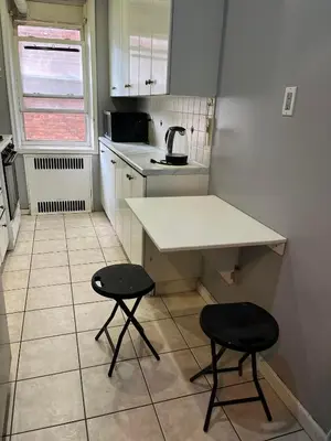 a small kitchen with a counter and two stools at 2 Large Bedrooms In Rego Park in Rego Park