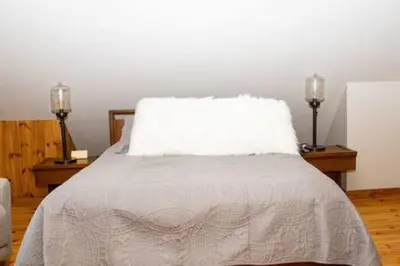 a bedroom with a bed with a white pillow and two lamps at Colgate Cabin #6 in Hamilton