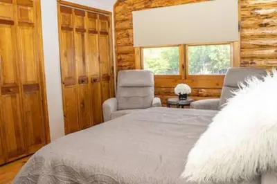 a bedroom with a bed and a chair and window at Colgate Cabin #6 in Hamilton