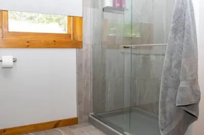 a glass shower in a bathroom with a window at Colgate Cabin #6 in Hamilton