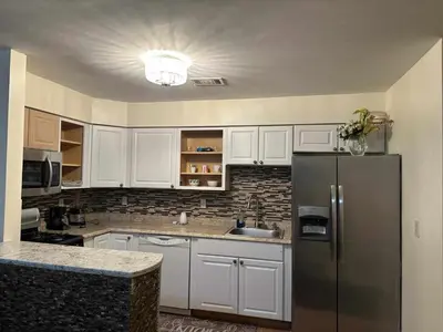 a kitchen with white cabinets and a stainless steel refrigerator at Room K Divine Villa and Resorts 5mins to EWR Airport and 4mins to Penn Station Newark, New York in Newark