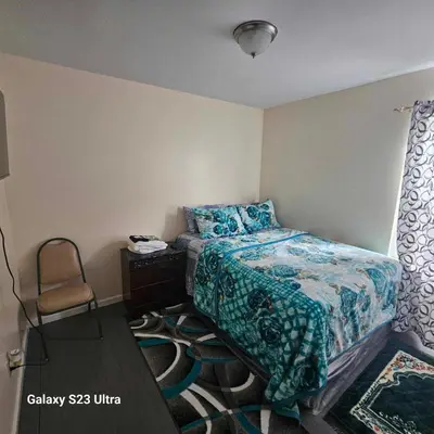 a small bedroom with a bed and a chair at Room K Divine Villa and Resorts 5mins to EWR Airport and 4mins to Penn Station Newark, New York in Newark