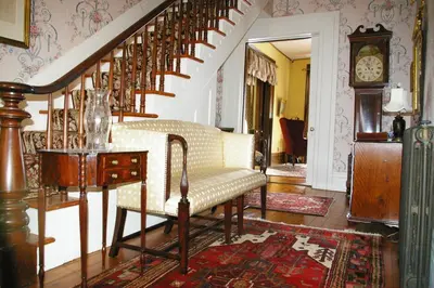 a living room with a staircase with a chair and a table at Oakcliff Bed and Breakfast in Halfmoon