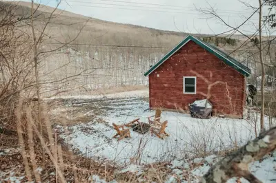 a red barn in a field with snow on the ground at Mountainscape: Peaceful & Skiing in Roxbury