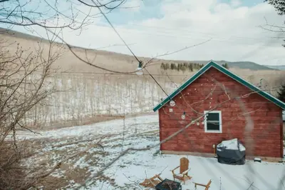 a red barn in a field with snow on the ground at Mountainscape: Peaceful & Skiing in Roxbury
