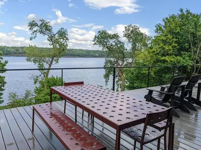 a table and chairs on a deck with a view of a lake at Hudson River Cliff House in Saugerties