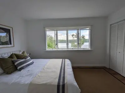 a white bedroom with a large bed and a window at Hudson River Cliff House in Saugerties
