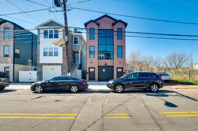 two cars parked in a parking lot in front of a building at Luxe Newark Retreat with Rooftop Deck Pets Welcome! in Newark