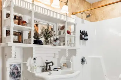 a white bathroom with a sink and a mirror at Hot Tub and Large Yard Elegant Deansboro Getaway in Deansboro