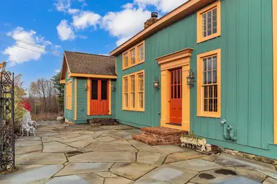 a green house with orange doors and a patio at Hot Tub and Large Yard Elegant Deansboro Getaway in Deansboro
