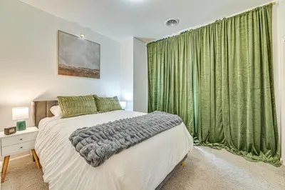 a bedroom with a bed and a window with green curtains at Downtown Albany Vacation Rental - Chic and Walkable! in Albany
