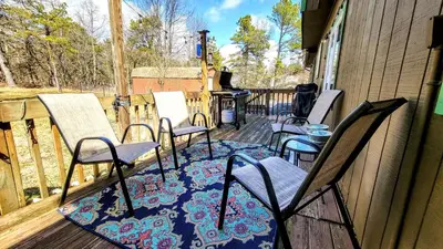 a group of chairs on a porch with a rug at The Wooden Nest by AvantStay Deck Big Yard w Hammocks Fire Pit in Long Pond