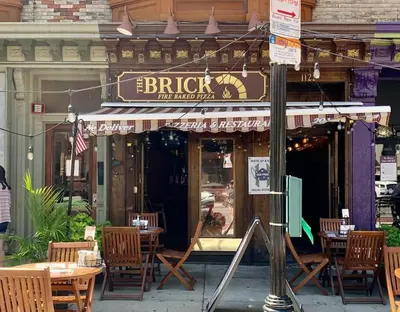 a restaurant with tables and chairs in front of a building at Sage Stay by the Train, We Pay Half Your Parking, 2 Queen Beds plus Sleeps 6 in Hoboken