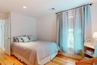 a bedroom with a bed with blue curtains and a window at Close to Copake Lake! 4-Season Escape with Sauna in Copake Falls