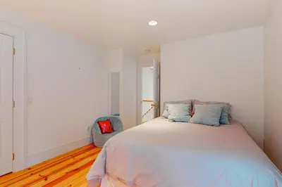 a white bedroom with a large bed with blue pillows at Close to Copake Lake! 4-Season Escape with Sauna in Copake Falls