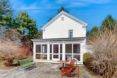 a white house with a patio with chairs and a table at Close to Copake Lake! 4-Season Escape with Sauna in Copake Falls