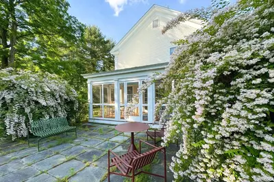 a patio with a table and chairs and flowers at Close to Copake Lake! 4-Season Escape with Sauna in Copake Falls