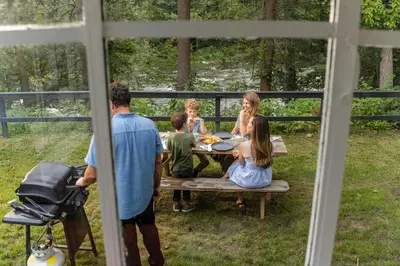 a family sitting at a table in the backyard at Perch Eagle House - Creek Access, Sauna, Mt views in Boiceville
