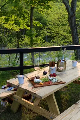 a picnic table with wine glasses and food on it at Perch Eagle House - Creek Access, Sauna, Mt views in Boiceville