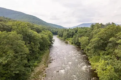 a river in the middle of a valley with trees at Perch Eagle House - Creek Access, Sauna, Mt views in Boiceville