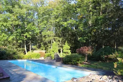 a swimming pool in a yard with trees at Woodstock Retreat- Heated Pool/Hot Tub/FirePit in Saugerties