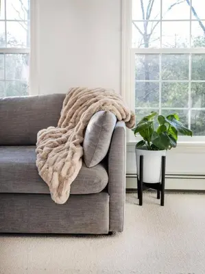 a blanket on the arm of a couch in a living room at Woodstock Retreat- Heated Pool/Hot Tub/FirePit in Saugerties