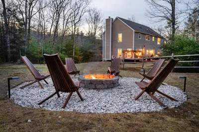 three chairs around a fire pit in front of a house at Woodstock Retreat- Heated Pool/Hot Tub/FirePit in Saugerties