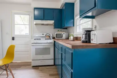 a kitchen with blue cabinets and a white stove top oven at Retro Retreat: 1br home w/ WFH desk, livingroom, and fire pit in Kingston