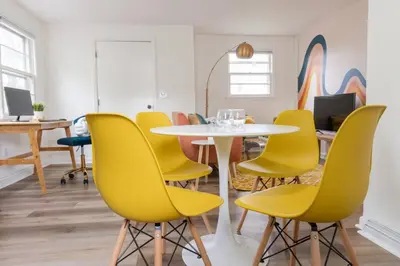a meeting room with a table and yellow chairs at Retro Retreat: 1br home w/ WFH desk, livingroom, and fire pit in Kingston
