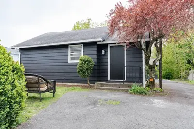 a black house with a bench in front of it at Retro Retreat: 1br home w/ WFH desk, livingroom, and fire pit in Kingston