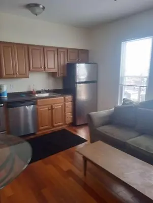 a kitchen with a couch and a stainless steel refrigerator at godlyone bedroom free parking in Schenectady