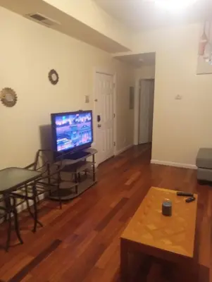 a living room with a television and a wooden floor at simple one bedroom free parking in Schenectady