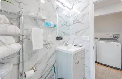 a bathroom with white marble walls and a sink at Exquisite 3 Bedrooms in Newark