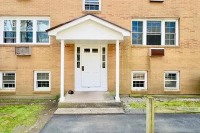 a brick house with a white door and a cat in front at Central Chic Crib in Manchester