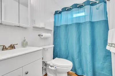 a bathroom with a toilet and a blue shower curtain at Central Chic Crib in Manchester