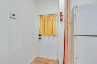 a kitchen with a white refrigerator and a yellow curtain at Dog-Friendly Fishkill Tiny House in Wine Country in Fishkill