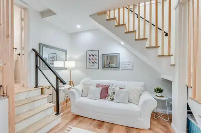 a living room with a white couch and stairs at Dog-Friendly Fishkill Tiny House in Wine Country in Fishkill