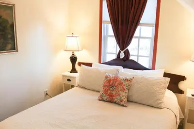 a bedroom with a bed with white pillows and a window at The Borland House Inn in Montgomery