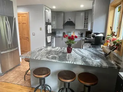 a kitchen with a counter with three stools at Where Memories Are Made in West Kill