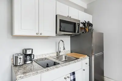 a kitchen with white cabinets and a stainless steel refrigerator at 73-919 New Studio UWS Doorman Gym in New York