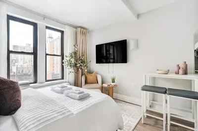 a white bedroom with a bed and a tv at 73-919 New Studio UWS Doorman Gym in New York