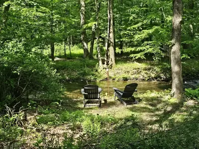 two chairs and a grill next to a stream at 30 Day Minimum Stay - Private Creekside Solace in East Stroudsburg