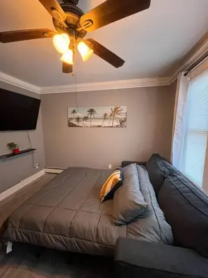 a bedroom with a couch and a ceiling fan at 4 Bedroom Apartment in Hillside