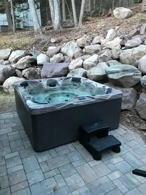 a hot tub sitting on a patio with rocks at Modern Chalet with Hot Tub and Lake Access in Monticello