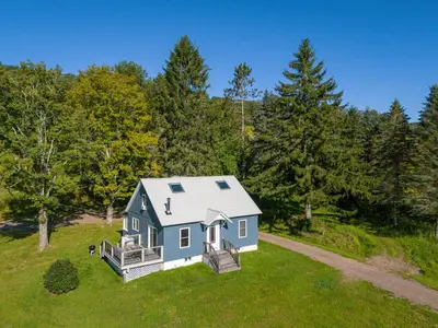 an aerial view of a blue house in a field at Chambers Hollow in Walton