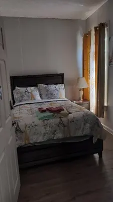 a bedroom with a bed and a lamp and a window at CLINTON HILLS - Newark in Newark